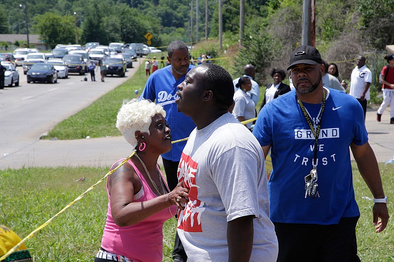 Tulsa resident Angie Pitts, left, tries to calm down others as law enforcement officials investigate near 46th Street North and Martin Luther King Jr. Boulevard, Friday, June 9, 2017 in Tulsa, Okla. Law officers in Tulsa fatally shot a man while trying to pick him up for a mental health issue, triggering a street protest and a corresponding show of force by police in riot gear. 