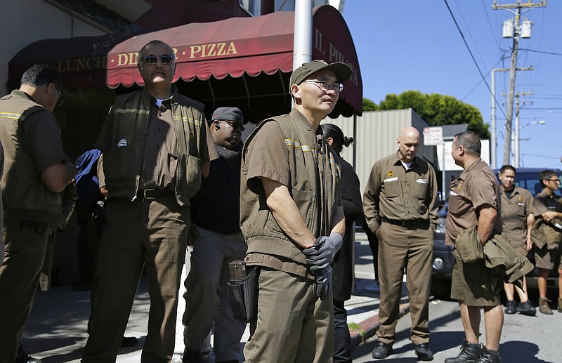 UPS workers gather outside a UPS package delivery warehouse where a shooting took place Wednesday, June 14, 2017, in San Francisco. A UPS spokesman says four people were injured in the shooting at the facility and that the shooter was an employee. 