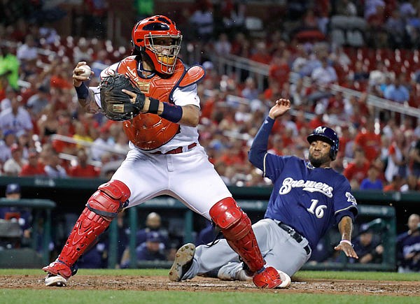 Domingo Santana of the Brewers scores as Cardinals catcher Yadier Molina looks to throw during the seventh inning of Wednesday night's game at Busch Stadium in St. Louis.