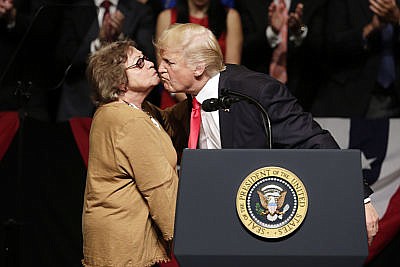 President Donald Trump kisses Martha Beatriz Roque, a Cuban political dissident, during a speech in Miami, Friday, June 16, 2017. Trump announced a revised Cuba policy aimed at halting the flow of U.S. cash to the country's military and security services while maintaining diplomatic relations.