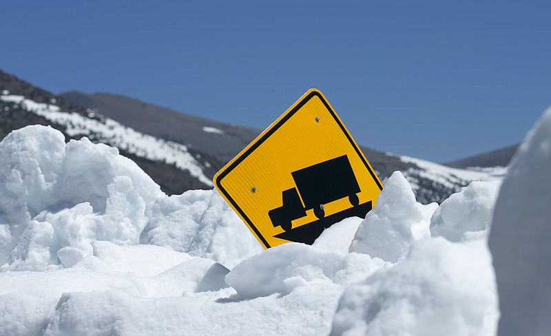 In this photo taken Tuesday, June 6, 2017, snow more than six feet deep nearly covers a warning sign alongside Highway 120 near Yosemite National Park, Calif. This year's heavy snowfall has crews working to clear Highway 120 as summer approaches, the only road through Yosemite that connects the Central Valley on the west side with the Owens Valley on the east side of the Sierra Nevada.