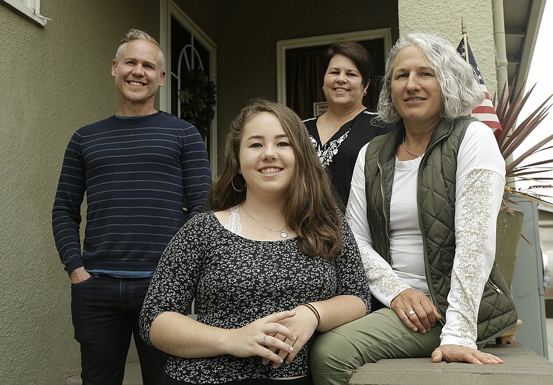 In this June 8, 2017 photo, Madison Bonner-Bianchi, center, poses for photos with her parents Mark Shumway, from left, Kimberli Bonner and Victoria Bianchi in Oakland, Calif. American courts have for decades granted some rights to grandparents, stepparents and others in children's lives, but parents have uniquely broad rights and responsibilities. Advocates say acknowledging a third parent reflects the realities of some families. Among them: a man seeking to remain in a paternal role after DNA shows someone else fathered the child he's raising; a terminally ill single mom joining forces with a couple to provide surviving parents for her child. (AP Photo/Jeff Chiu)