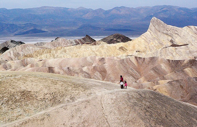 Tourists walk along a ridge at Death Valley National Park, California. Death Valley National Park was expected to reach its first 120-degree day of the year on Sunday, and temperatures could creep toward 124 by Tuesday as the sweltering system envelopes much of the region.