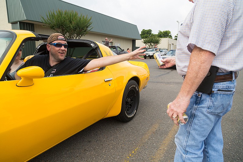 A man in a Trans-Am reaches for a Coors beer that Rickey Richardson moves just out of his reach Sunday on Broad Street in Texarkana, Ark. Board members of the Four States Auto Museum gave drivers in the Bandit Run 2017 a symbolic Coors before they started off to Atlanta, echoing the plot of the 1977 film "Smokey and Bandit" which centers on bootlegging 400 cases of Coors from Texarkana to Georgia.