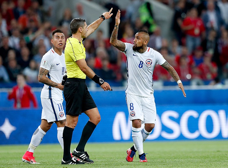 Chile's Arturo Vidal, right, and Eduardo Vargas argue with referee Demir Skomina during the Confederations Cup, Group B soccer match between Cameroon and Chile, at the Spartak Stadium in Moscow, Sunday, June 18, 2017.