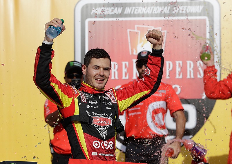 Kyle Larson raises his arms after exiting his car after winning a NASCAR Sprint Cup series auto race, Sunday, June 18, 2017, in Brooklyn, Mich. 