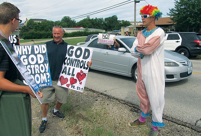Westboro Baptist Church member Chris Jaques, middle, chats with another member of the church, left, while Steve Thoenen (wearing clown costume) counter-protests Sunday at the Westboro Baptist's picket outside Bible Baptist Church. 