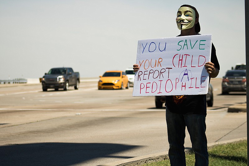 An anonymous man urges people to report child molesters Tuesday as he stands near Richmond Road. He said he is doing this peacefully to raise awareness of how many incidents go unreported. He said he has had family members go through such incidents. When asked what his name was, he said "I am just a human being."