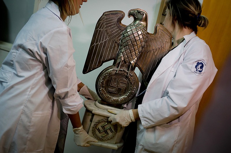 Members of the federal police carry a Nazi statue at the Interpol headquarters in Buenos Aires, Argentina, Friday, June 16, 2017. In a hidden room in a house near Argentina's capital, police discovered on June 8th the biggest collection of Nazi artifacts in the country's history. Authorities say they suspect they are originals that belonged to high-ranking Nazis in Germany during World War II.