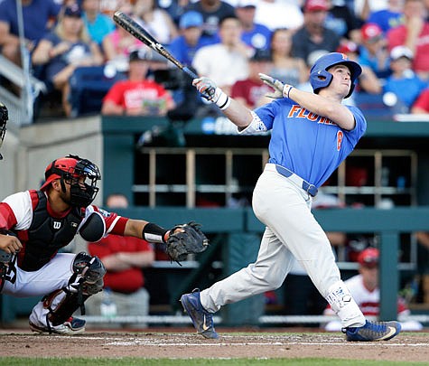 Florida's Deacon Liput follows through on a three-run home run in front of Louisville catcher Colby Fitch in the fourth inning of Tuesday night's College World Series game in Omaha, Neb. Fitch is a former Hickman Kewpie.