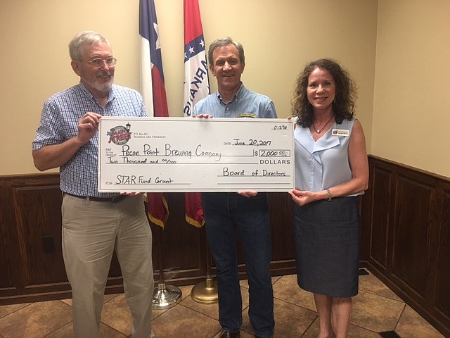 Dr. Charles Blankenship, left, and Ina McDowell, right, of Main Street Texarkana present Bill Scurlock of Pecan Point Brewing and Gastropub with a check for $2,000 from Main Street Texarkana's new STAR Grant Fund.
