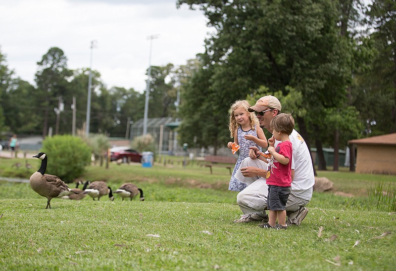 Sky Robertson and his two children, Aurora, 3, and Rainan, 2, feed the ducks June 21 at Spring Lake Park in Texarkana, Texas. The city began a dredging process of the pond this month and are relocating the ducks and geese.