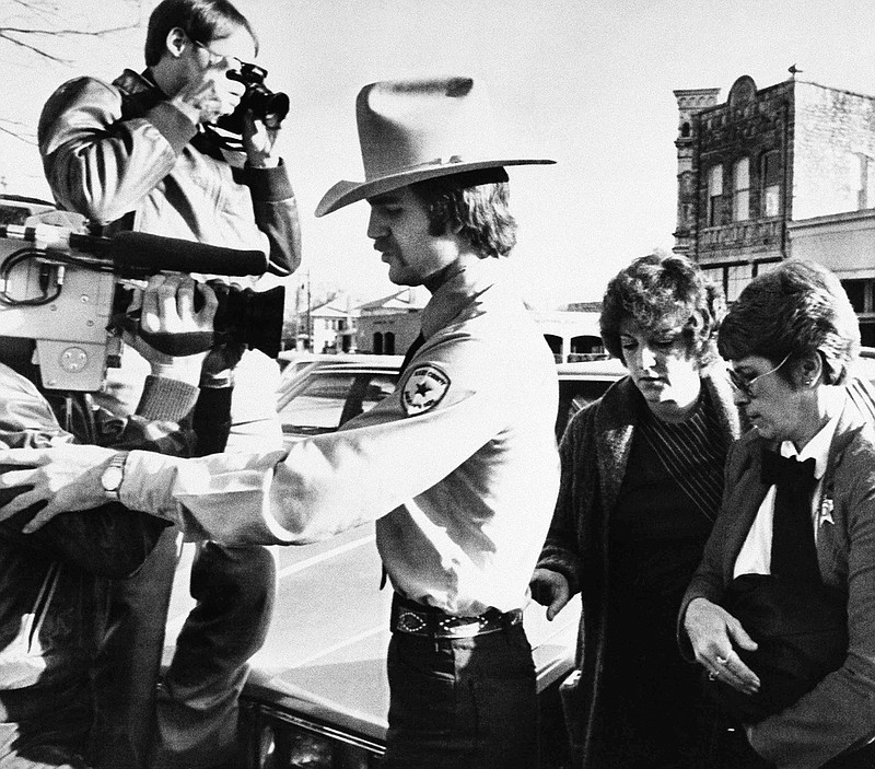 In this Feb. 16, 1984, file photo, nurse Genene Jones, in custody of Kerr County Deputy Clay Barton, left, and Williamson County Deputy Loretta Pickett, right, arrives at Williamson County Courthouse in Georgetown, Texas, where she was sentenced to 99 years in prison by the same jury that found her guilty of killing a 15-month-old baby girl by a lethal injection. The former Texas nurse who prosecutors said may be responsible for the deaths of up to 60 young children has been indicted on a murder charge for the second time in recent weeks. Prosecutors in San Antonio said in a statement that 66-year-old Jones was indicted Wednesday, June 21, 2017, in the 1981 death of 2-year-old Rosemary Vega. She was charged with a separate count of murder last month in the death of an 11-month-old boy. 