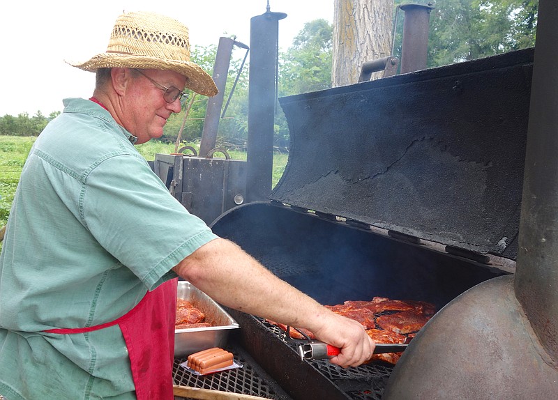 Tebbetts Picnic organizer Sam Richards slaps a few pork steaks on the grill on Friday, June 23, 2017.