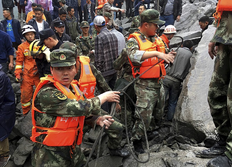 Emergency personnel work at the site of a massive landslide in Xinmo village in Maoxian County in southwestern China's Sichuan Province, Saturday, June 24, 2017. Dozens of people are feared buried by a landslide that unleashed huge rocks and a mass of earth that crashed into their homes in southwestern China early Saturday, a county government said.(Chinatopix via AP)