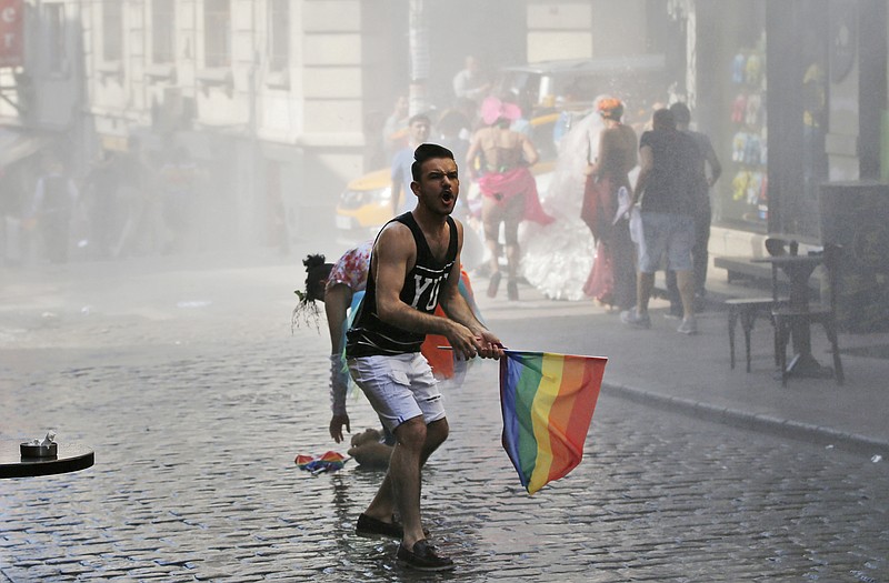 FILE - In this Sunday, June 28, 2015 file photo, a participant of the Pride Week march in Istanbul, reacts as others flee after Turkish police use a water canon to disperse them. For several years, Pride Week in Istanbul attracted tens of thousands of participants, making it one of largest gatherings celebrating gay, lesbian and transgender rights and diversity in the Muslim world. That changed suddenly in 2015, when authorities, citing security concerns, banned gay and trans-gender pride events chasing away shocked participants trying to converge on central Taksim Square with tear gas and water cannons. (AP Photo/Emrah Gurel, File)