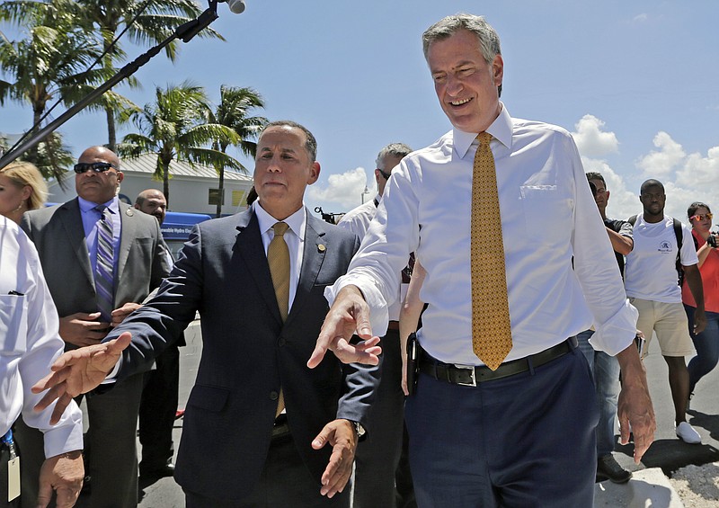 New York City Mayor Bill de Blasio, right, and Miami Beach Mayor Philip Levine, left, talk during a tour where the city has raised streets and installed pumps to combat rising tides, Friday, June 23, 2017, in Miami Beach, Fla. The U.S. Conference of Mayors opens its annual meeting Friday in Miami Beach. Mayors of cities with populations of 30,000 or more will discuss plans to reduce the nation's carbon footprint and protect immigrant families. (AP Photo/Alan Diaz)