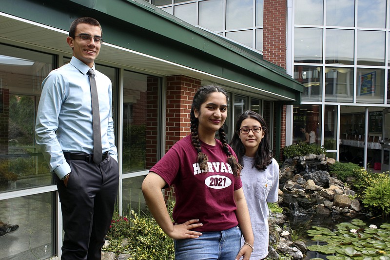 In this photo taken Thursday, June 15, 2017, in Brentwood, N.Y., high school valedictorians Michael Simoes, left, Reeda Iqbal, center, and co-salutatorian Saray Vazquez pose at the high school. The students are graduating after a year that saw several gang killings in their Long Island community, including five victims who attended Brentwood High School. (AP Photo/Frank Eltman)