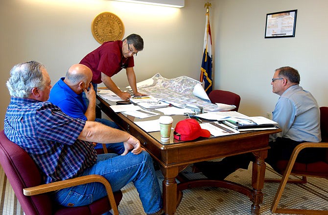 Commissioners Randy Kleindienst, left, and Gary Jungermann watch intently as Roger Fischer points out the Jefferson City-area businesses that might use a port, if one was built in the area. Jefferson City Area Chamber of Commerce President Randy Allen also attended the meeting, during which commissioners voted to help pay for a feasibility study for the proposed port.