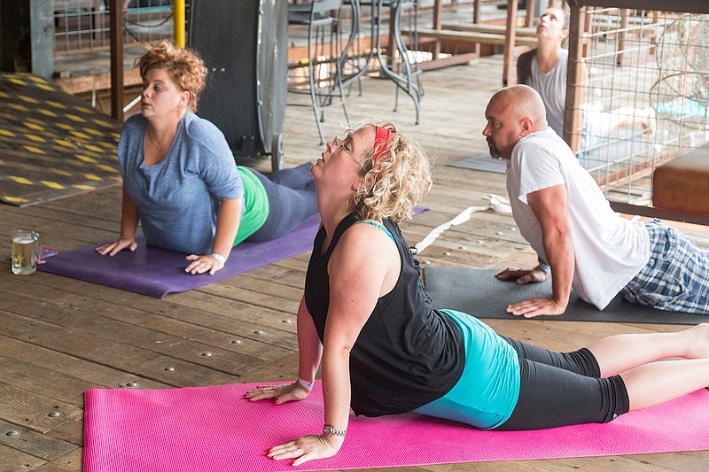 Students of Colleen Narens' Yoga and Beer class hold Urdhva Mukha Svanasana on Saturday at Scottie's Grill. Narens decided to do a Yoga and Beer class as a way to encourage people who wouldn't normally try yoga to give it a shot. The next class will be at 10 a.m. on July 8 at Scottie's Grill.
