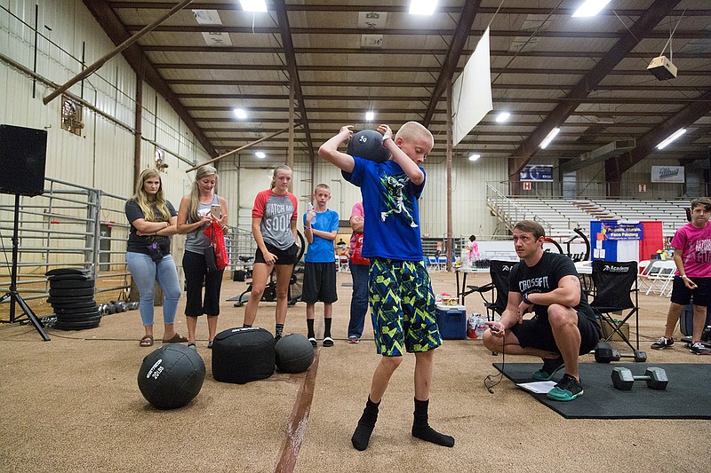 Garrett Greenlaw, 13, does a 1-minute challenge of ground-to-overheads with a 20-pound medicine ball Saturday at the Fitness Expo at the Four States Fairgrounds. The event showcased local gyms and health product companies. 
