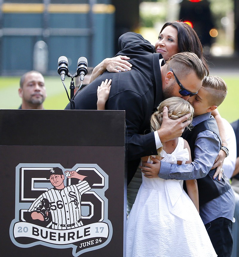 Former Chicago White Sox pitcher Mark Buehrle, left, is hugged by his family, wife Jamie, top, daughter Brooklyn, and son Braden after his No. 56 was retired during ceremonies before a baseball game between the White Sox and the Oakland Athletics Saturday, June 24, 2017, in Chicago. 