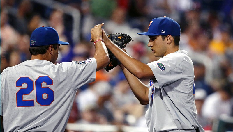 Florida pitcher Alex Faedo, right, is greeted by Nick Horvath (26) as he is pulled in the eighth inning of an NCAA College World Series baseball elimination game against TCU in Omaha, Neb., Saturday, June 24, 2017. 