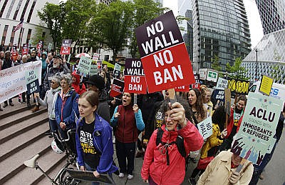 In this May 15, 2017 file photo, protesters wave signs and chant during a demonstration against President Donald Trump's revised travel ban, outside a federal courthouse in Seattle. The Supreme Court is letting the Trump administration enforce its 90-day ban on travelers from six mostly Muslim countries, overturning lower court orders that blocked it. The action Monday, June 26, 2017, is a victory for President Donald Trump in the biggest legal controversy of his young presidency.