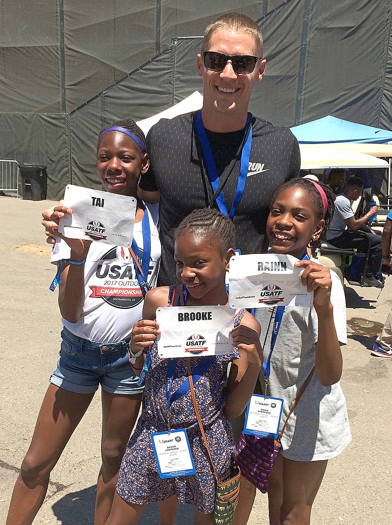 In this photo taken Saturday, June 24, 2017, Decathlete Trey Hardee poses with the Sheppard sisters, Tai, 12, left, Brooke, 9, center and Rainn, 11, right, at the U.S. Track and Field Championships, in Sacramento, Calif. The once-homeless sisters were guests at the nationals over the weekend, meeting their idols and given the gold medal Justin Gatlin earned in the 100 meters. The Sheppard siblings rose to prominence in track and field, with their exploits bringing them medals, TV appearances and even a magazine cover.