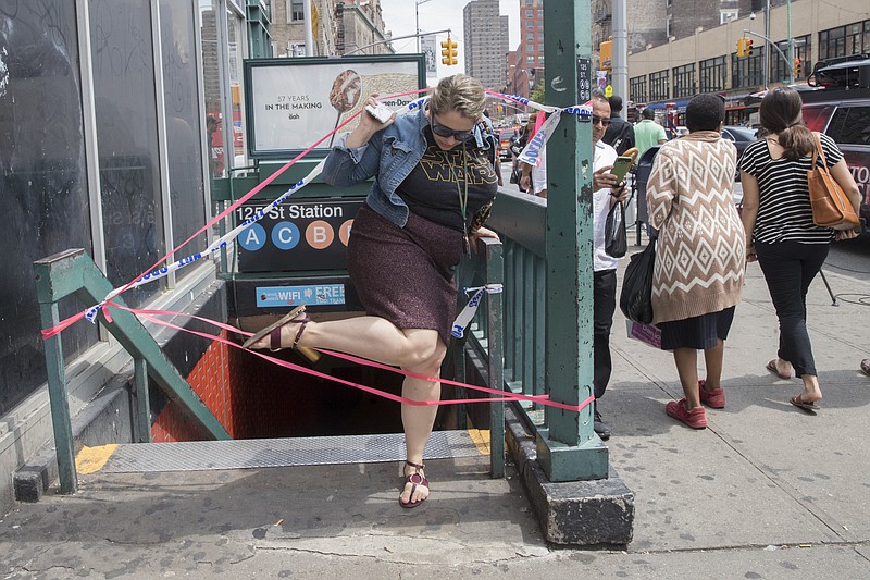 A commuter exits a closed off station after a subway train derailment, Tuesday, June 27, 2017, in the Harlem neighborhood of New York. A subway train derailed near a station in Harlem on Tuesday, frightening passengers and resulting in a power outage as people were evacuated from trains along the subway line. The Fire Department of New York said a handful of people were treated for minor injuries at around 10 a.m. It said there was smoke but no fire. Delays were reported throughout the subway system. (AP Photo/Mary Altaffer)