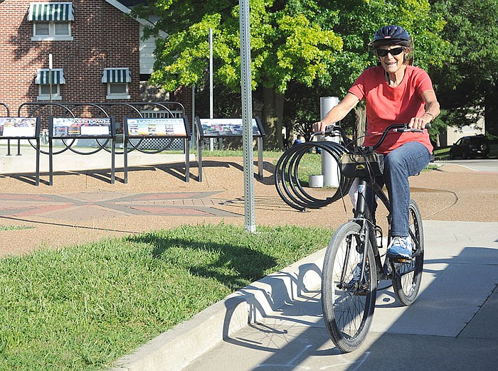 A woman rides her bike past "bike plaza" at the intersection of Main and Clay streets in Jefferson City on Monday. The Jefferson City Convention and Visitor Bureau has ordered 31 new "Discover JC" bike racks to install throughout the city.