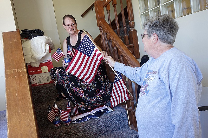 Sharin White (right) hands a flag to her daughter Michele while decorating a window on Monday morning. Both are VFW Post 2657 Auxiliary members. They decorated the window, across the street from the Callaway County Courthouse, with information about the U.S. Constitution. They will decorate another window next Monday on Court Street with American flags.