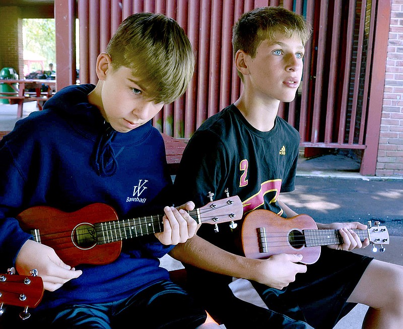 Connor Shamany, left, and Ethan Brennan, both members of the summer park program at Whispering Willows Park, learn how to play a ukulele while attending a workshop provided by Simple Gifts, a group of 2 women who play 12 instruments, Tuesday, June 27, 2017, at the Conyngham park in Drums, Pa.
