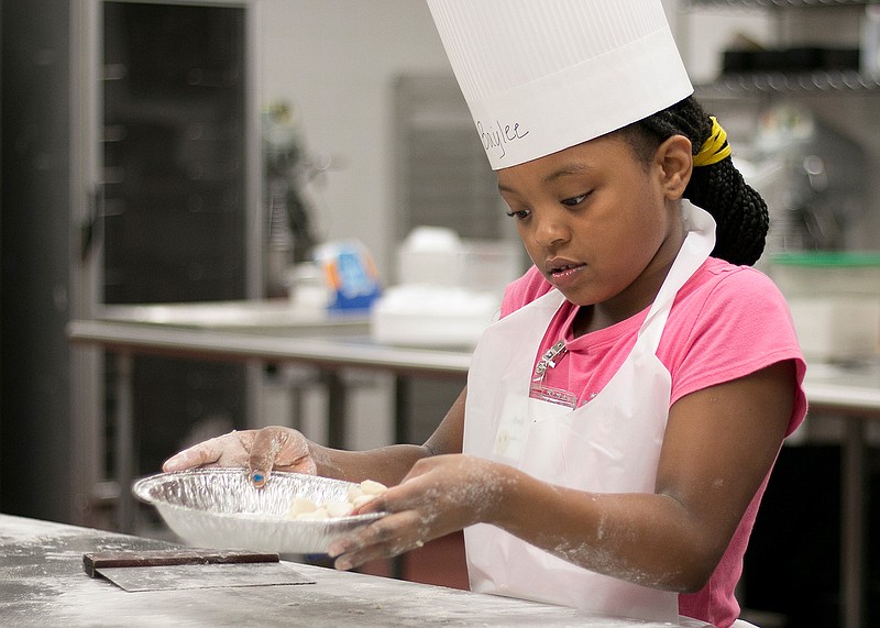 Baylee Gentry, 8, shakes flour into her gnocchi dumplings during her first year at Kids College on Wednesday at Texarkana College. The annual Kids College program provided a culinary class taught by chef Sheila Lynn to give kids the opportunity to learn to make various dishes.
