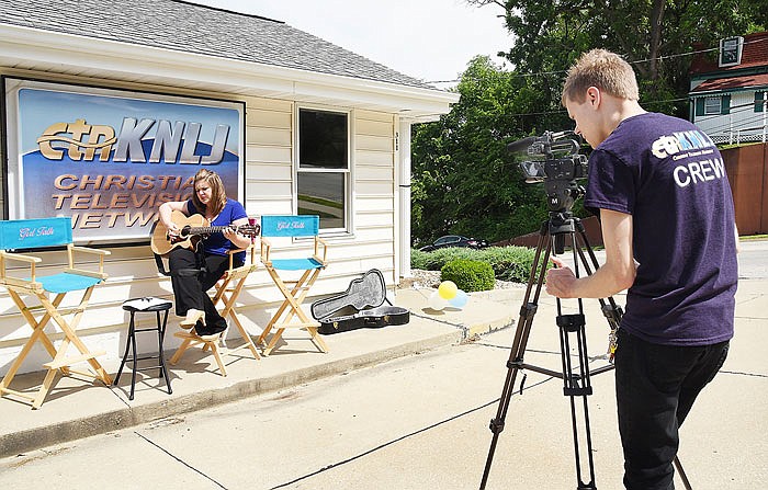 Angela Reimund plays guitar and sings as Austin Phillips records her performance. Both work at local Christian television station CTN-KNLJ, which is marking its 10th anniversary of operations. 