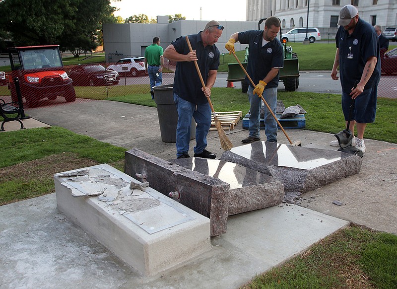 Secretary of State staff members pick up pieces of the the newly-installed 10 Commandments monument on the State Capitol grounds after it was toppled by a man driving a car before dawn on Wednesday, June 28, 2017.