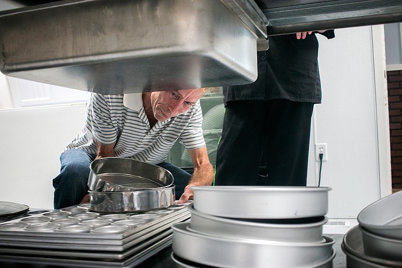 Rodger Kennedy crouches down to put up pots and pans on Wednesday in Be the Blessing Bakery's new kitchen. Be the Blessing Bakery is a culinary job training program at the Randy Sams' Outreach Shelter.
