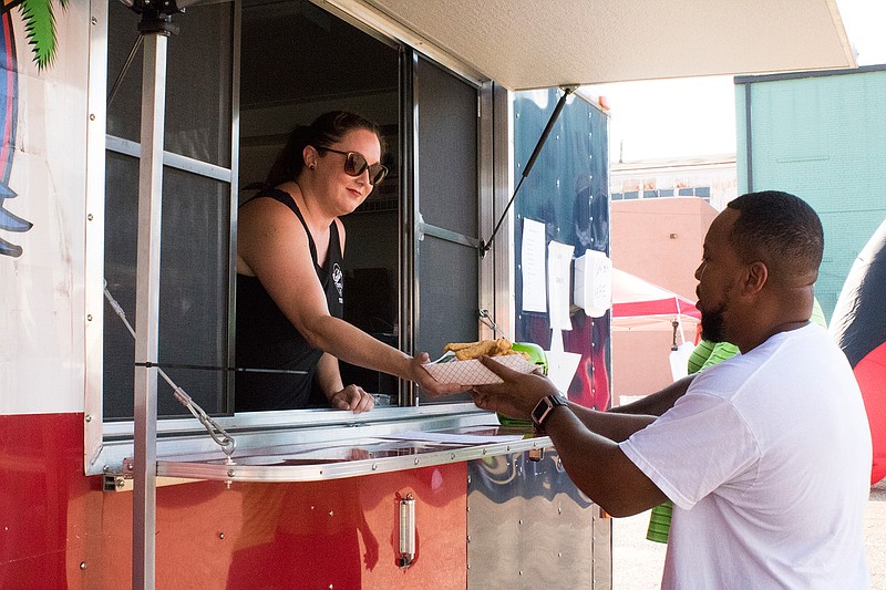 Kim Greening gives George Hanson his freshly cooked catfish from the Scottie's Grill food truck on Friday afternoon at the Texarkana Cajun Catfish Festival. The festival continues today from noon to 11 p.m.