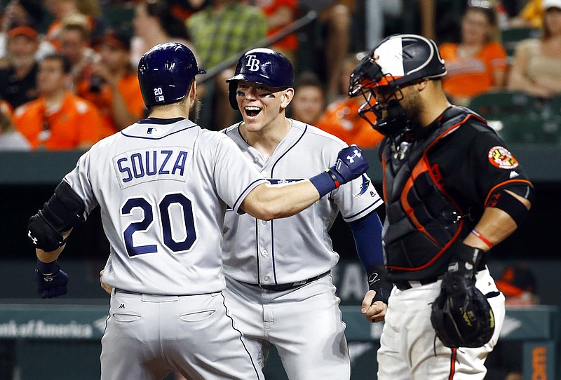 Tampa Bay Rays' Logan Morrison, center, greets Steven Souza Jr. at home plate next to Baltimore Orioles catcher Welington Castillo, right, after scoring on Souza's three-run home run during the 10th inning of a baseball game in Baltimore, Friday, June 30, 2017. Tampa Bay won 6-4 in 10 innings. 