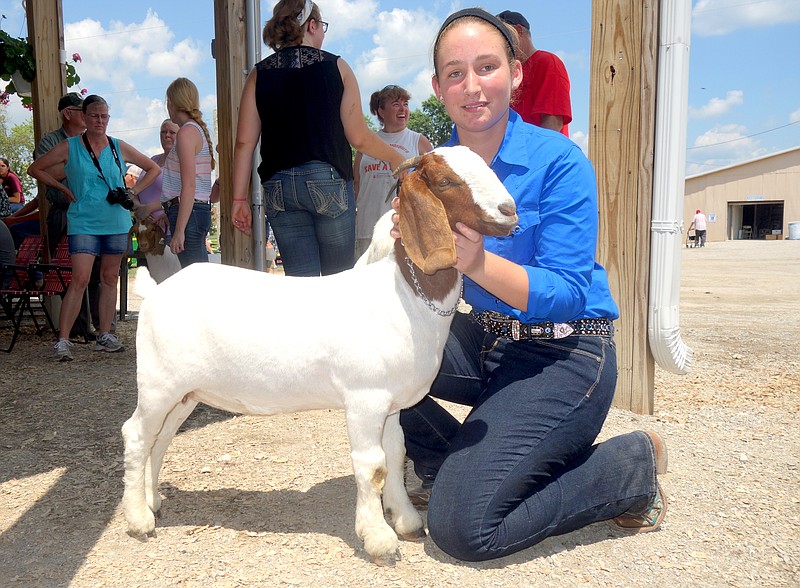 Rachel Hasty poses with her prize-winning Boer goat before reentering the arena to compete in the showmanship class. Her goat was named the Supreme Champion Doe.