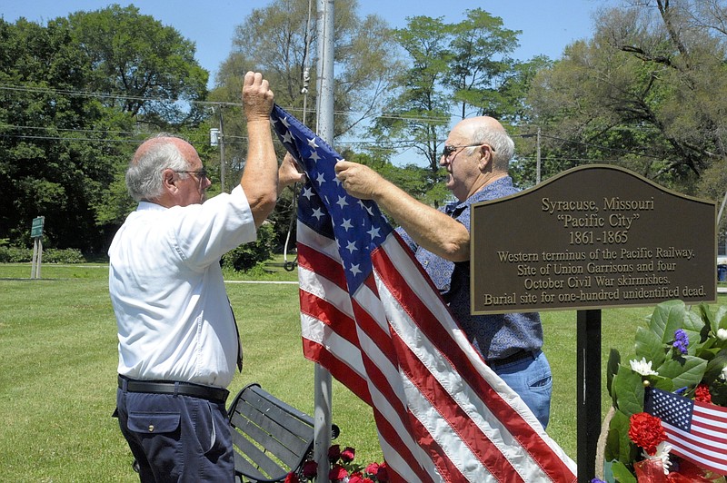 Syracuse residents prepare to raise the U.S. flag next to a maker memorializing the Morgan County town residents' sacrifices in the Civil War.