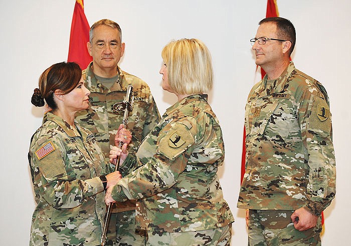 Warrant Officer (WO1) Shelby Shaffer, foreground right, hands a saber to CW5 Michelle Struempf, left, after which it will be handed to Adjutant Gen. Steve Danner, background middle, then on to CW5 Patrick Muenks, the incoming state command chief warrant officer before it's returned to Shaffer. Struempf, who retires Saturday, has been command chief warrant officer since October 2012.