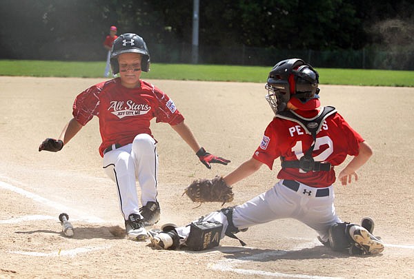 Jefferson City's Caiden Sanford (left) slides safely into home plate under the tag of Daniel Boone National catcher Dawson Peters during the first inning of the first championship game Sunday in the Little League 11U District 4 Tournament at Duensing Field.