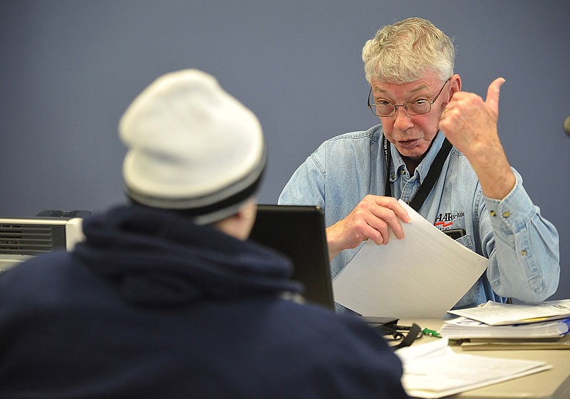 In this February 13, 2015 file photo, Lewis Hancock, one of several volunteers from the Jefferson CIty Chapter of the AARP helps a local resident with her income tax paperwork.