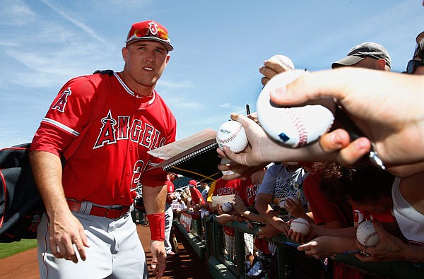 Angels center fielder Mike Trout pauses as he signs autographs for fans prior to a spring training baseball game against the Reds earlier this year in Goodyear, Ariz.