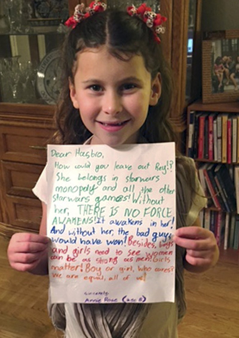 In this January 2016 photo provided by Carrie Goldman, her daughter, Annie Rose, holds a letter in Evanston, Ill., that she wrote to Hasbro asking why the female character Rey was omitted from a Monopoly set based on "Star Wars: The Force Awakens," when she is a main character and crucial to the story. Hasbro responded that they would add Rey to a Star Wars version of Monopoly by the end of the year. Eighteen months later, Annie Rose and others are still waiting. (Carrie Goldman via AP)