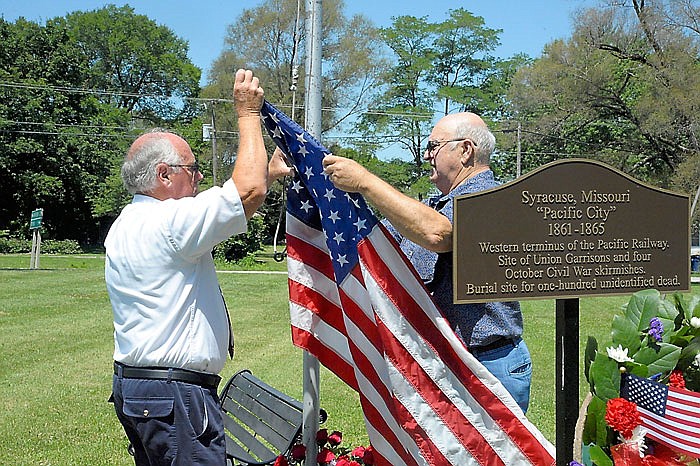 Syracuse residents prepare to raise the U.S. flag next to a maker memorializing the Morgan County town residents' sacrifices in the Civil War.