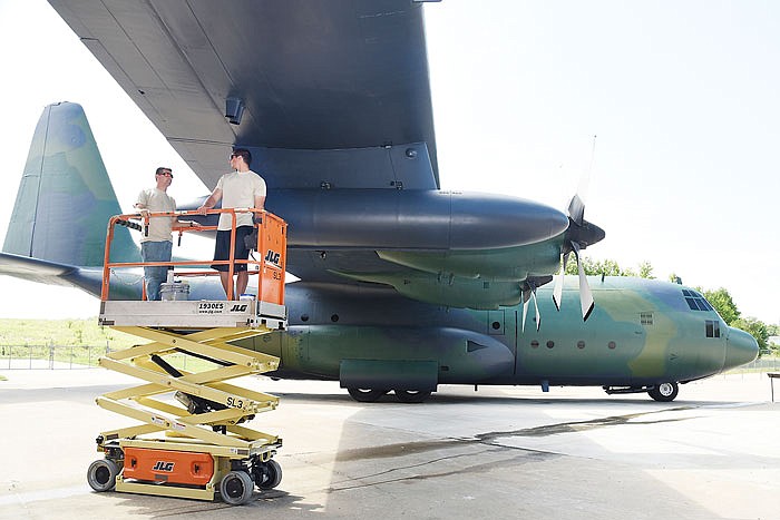 Tech Sgt. Trevor Wilson, left, and Senior Airman Ethan Nolte ride the scissor-scissor lift to the next spot to touch up. Both are members of the 139th Maintenance Squadron, of St. Joseph, who've spent the last several days repainting the C-130 airplane parked in front of the Museum of Missouri Military History. 