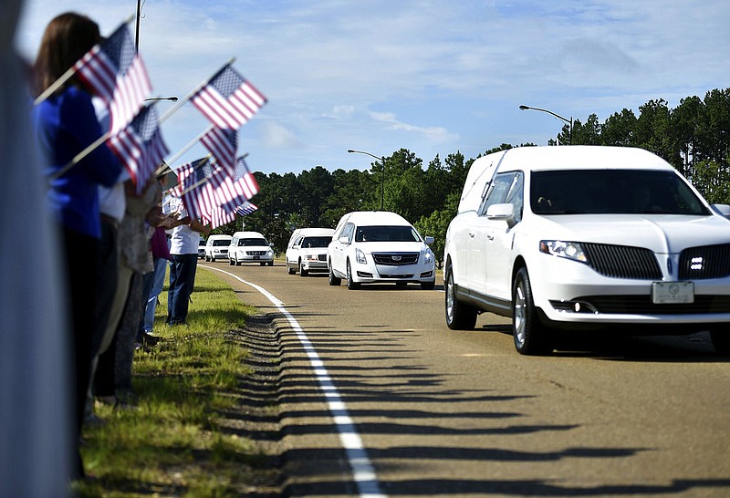 Supporters hold American flags on the side of Airport Road in Jackson, Miss., Thursday, July 13, 2017, as hearses carry the remains of the 16 service members who died in a plane crash in Leflore County, on Monday to the Air National Guard base for their final flights home. (Justin Sellers/The Clarion-Ledger via AP)