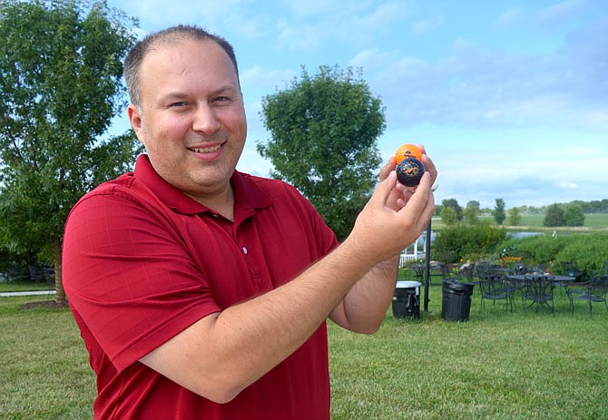 Darren Wernig, city of Fulton's public information officer, demonstrates a partial eclipse with commemorative golf balls. The golf balls will be sold at the Tanglewood Golf Course beginning Aug. 1, he said.